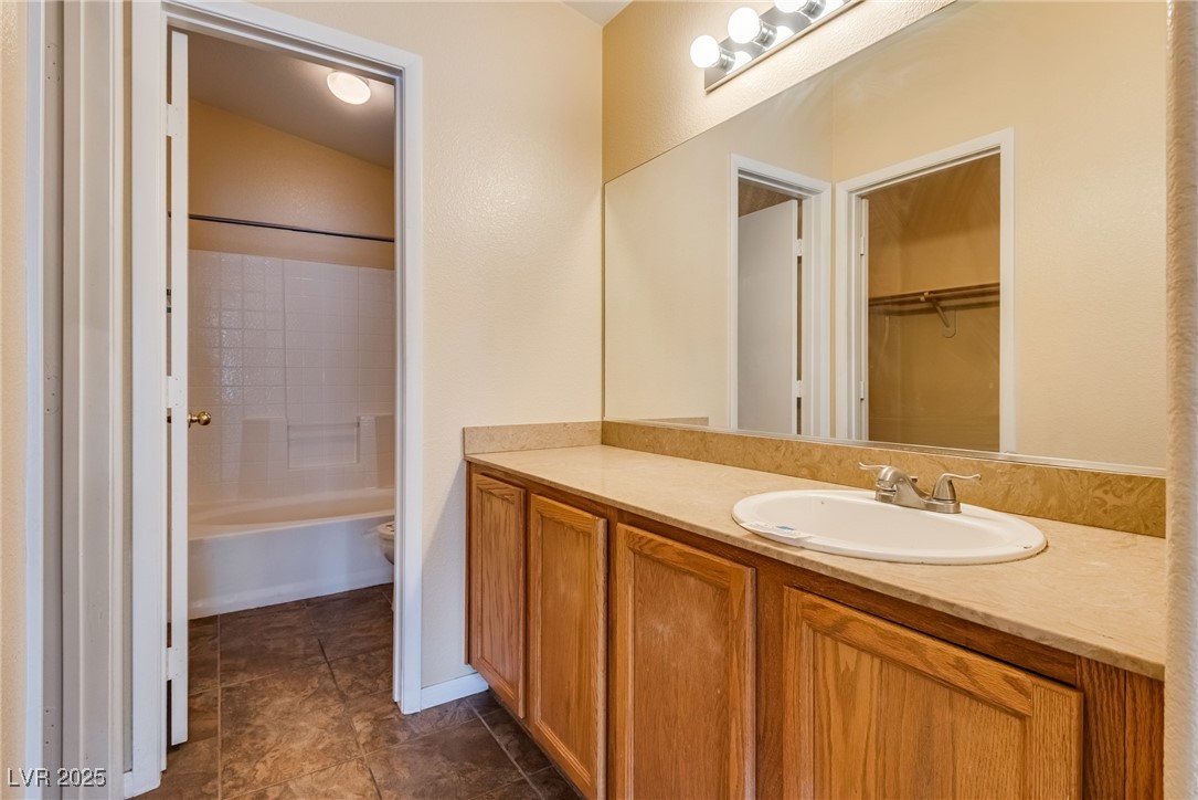 6354 Rusticated Stone Avenue, Unit 101 Henderson, NV 89011 - Photo 12 of 21 Bathroom with vanity, bathtub / shower combination, a walk in closet, and dark tile patterned floors