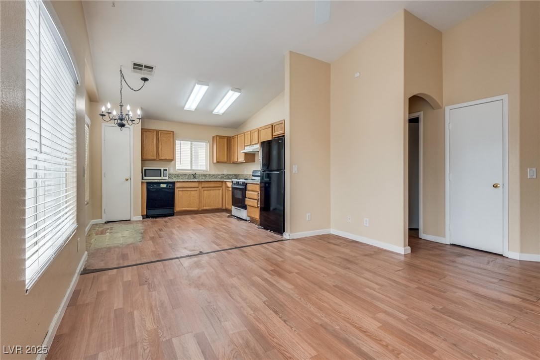 6354 Rusticated Stone Avenue, Unit 101 Henderson, NV 89011 - Photo 21 of 21 Kitchen with light wood-type flooring, black appliances, open floor plan, light countertops, and hanging light fixtures
