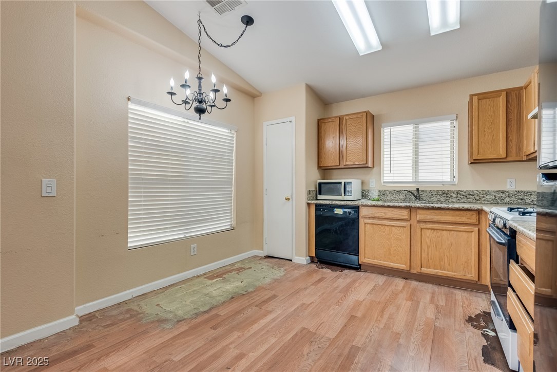 6354 Rusticated Stone Avenue, Unit 101 Henderson, NV 89011 - Photo 7 of 21 Kitchen featuring light wood-style flooring, white appliances, hanging light fixtures, a chandelier, and light stone countertops
