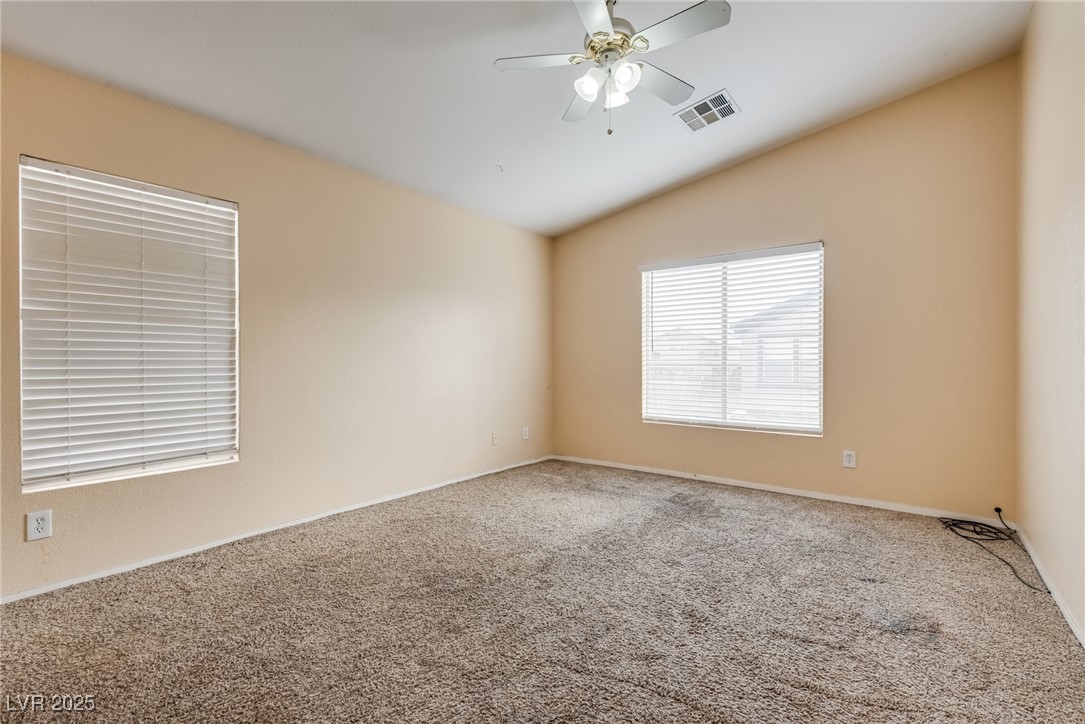 6354 Rusticated Stone Avenue, Unit 101 Henderson, NV 89011 - Photo 9 of 21 Unfurnished room featuring vaulted ceiling, carpet, and a ceiling fan