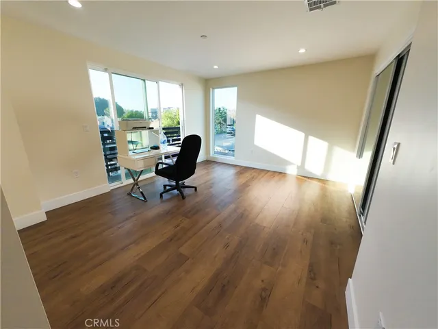 a view of a workspace with wooden floor and furniture