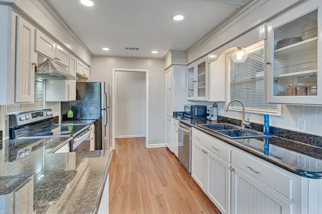 a large kitchen with stainless steel appliances granite countertop a lot of counter space and wooden floors