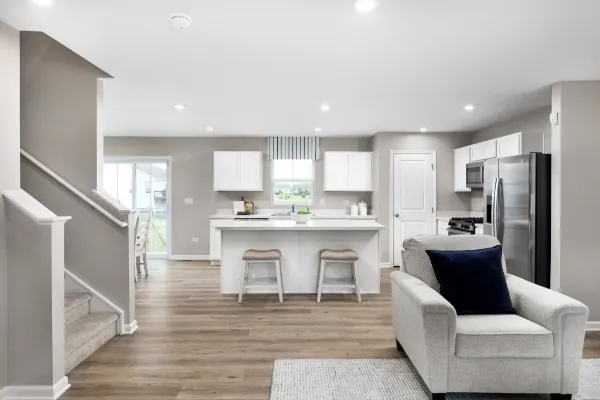 a living room with stainless steel appliances kitchen island granite countertop a refrigerator a sink a stove and white cabinets with wooden floor