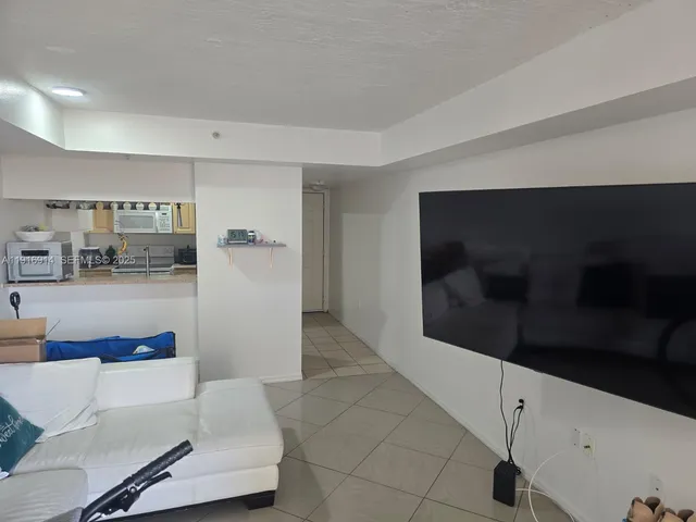 a living room with stainless steel appliances kitchen island granite countertop a refrigerator and a stove top oven