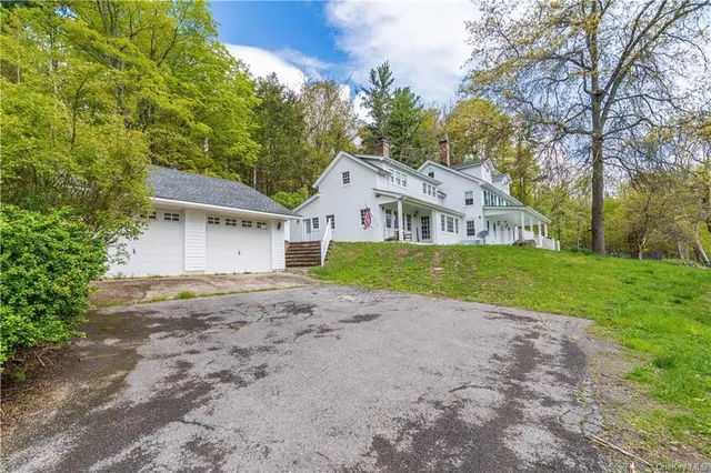 a view of an house with a big yard and large trees