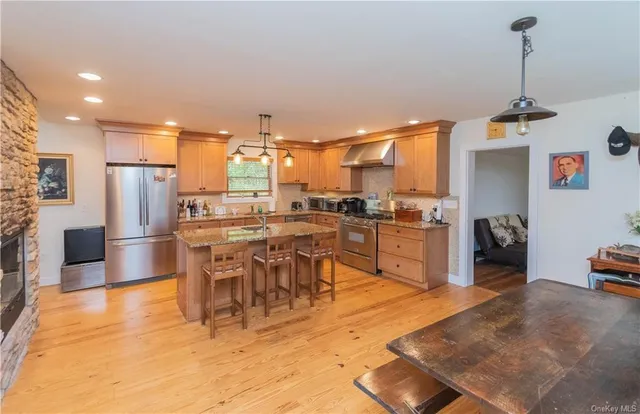 a kitchen with stainless steel appliances kitchen island granite countertop dining table chairs and a refrigerator
