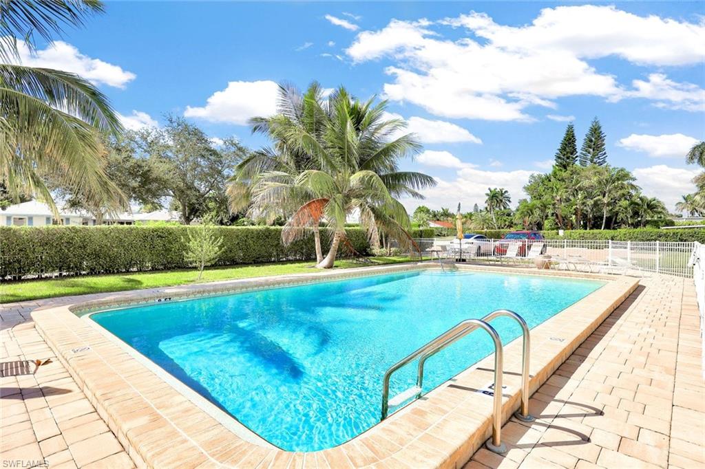 2000 Alamanda Drive, Unit 104 Naples, FL 34102 - Photo 15 of 32 a view of swimming pool with seating area and trees in the background