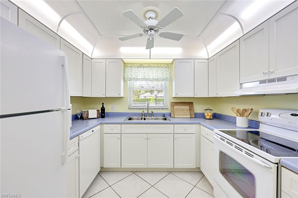 2000 Alamanda Drive, Unit 104 Naples, FL 34102 - Photo 23 of 32 a kitchen with a white cabinets and white appliances