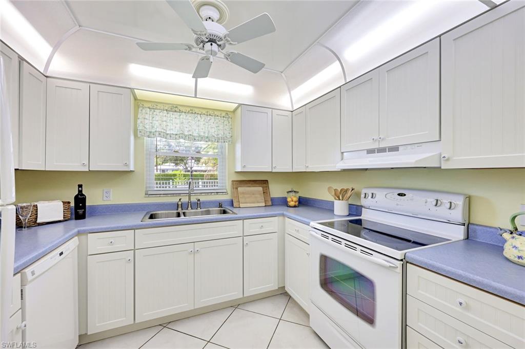 2000 Alamanda Drive, Unit 104 Naples, FL 34102 - Photo 24 of 32 a kitchen with a sink dishwasher a stove and white cabinets