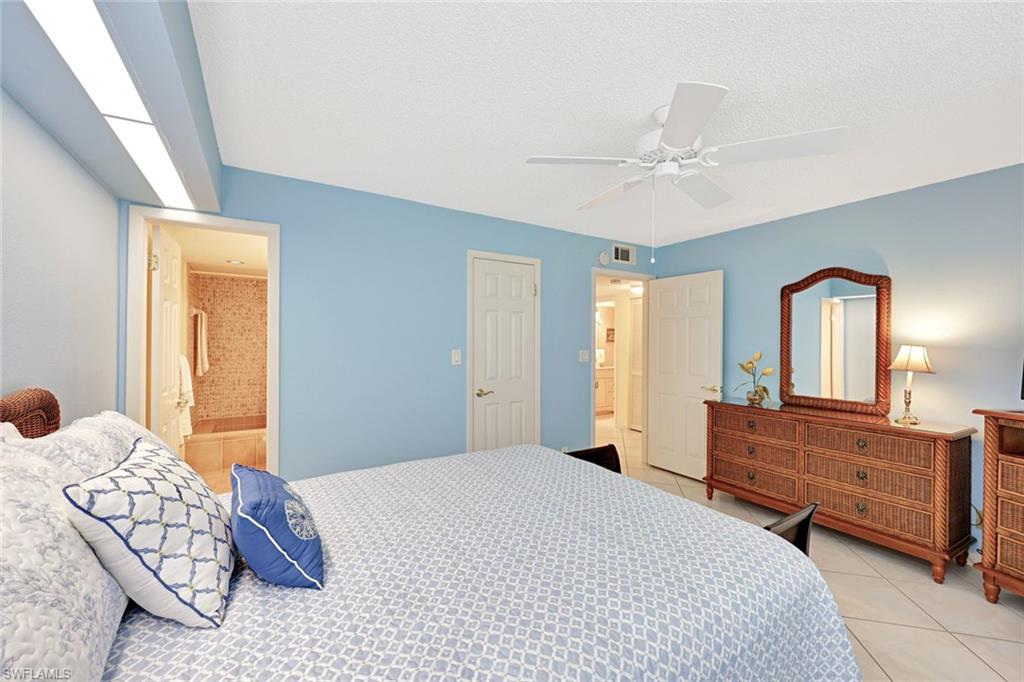 2000 Alamanda Drive, Unit 104 Naples, FL 34102 - Photo 27 of 32 a bedroom with a large bed and a chandelier