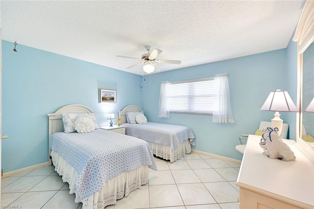 2000 Alamanda Drive, Unit 104 Naples, FL 34102 - Photo 29 of 32 a bedroom with two beds and a chandelier