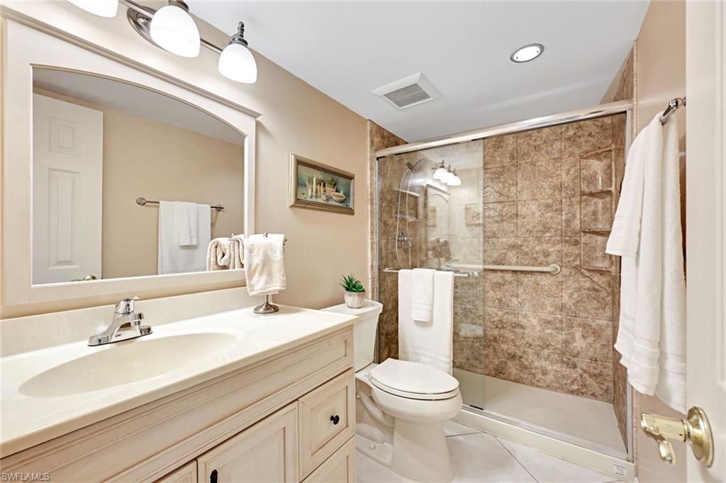 2000 Alamanda Drive, Unit 104 Naples, FL 34102 - Photo 30 of 32 a bathroom with a sink toilet a mirror and shower