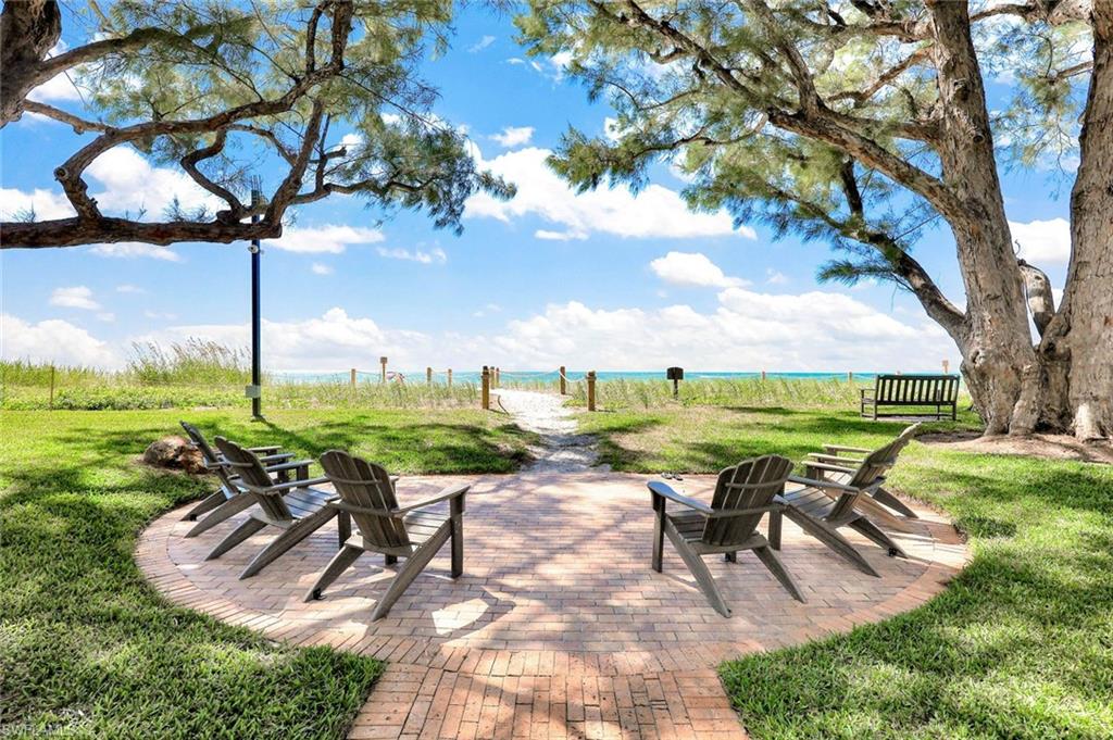 2000 Alamanda Drive, Unit 104 Naples, FL 34102 - Photo 6 of 32 a view of a patio with table and chairs and a big yard