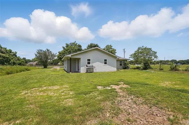 a front view of house with yard and trees in the background
