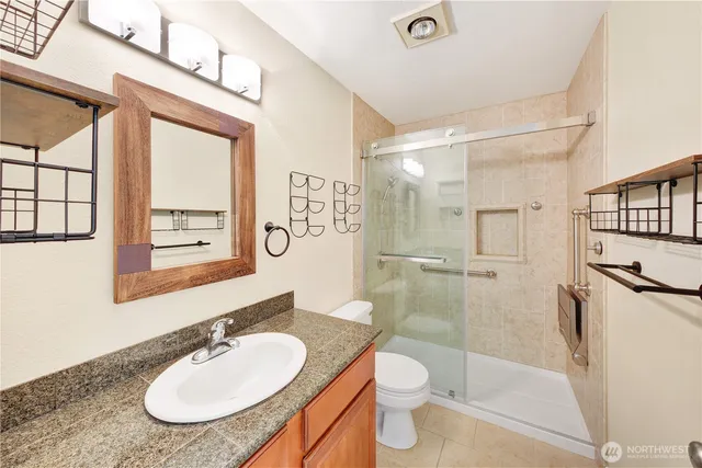 a bathroom with a granite countertop sink toilet a mirror and shower