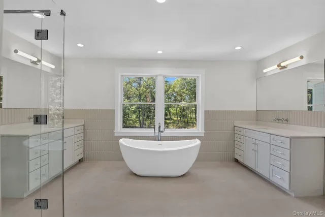 a spacious bathroom with a double vanity sink a large mirror and a bathtub