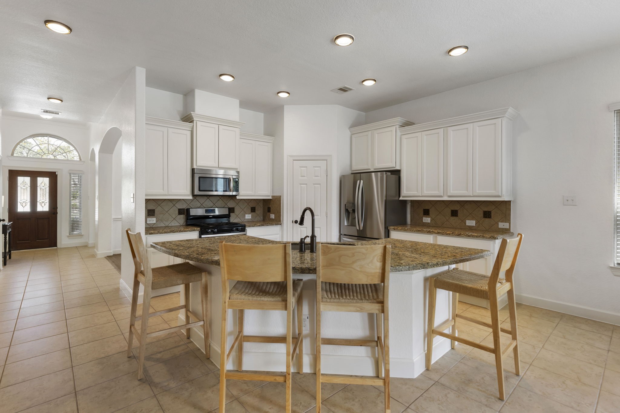 71 Sagamore Ridge Place The Woodlands, TX 77389 - Photo 12 of 34 a kitchen with stainless steel appliances kitchen island granite countertop a refrigerator and microwave