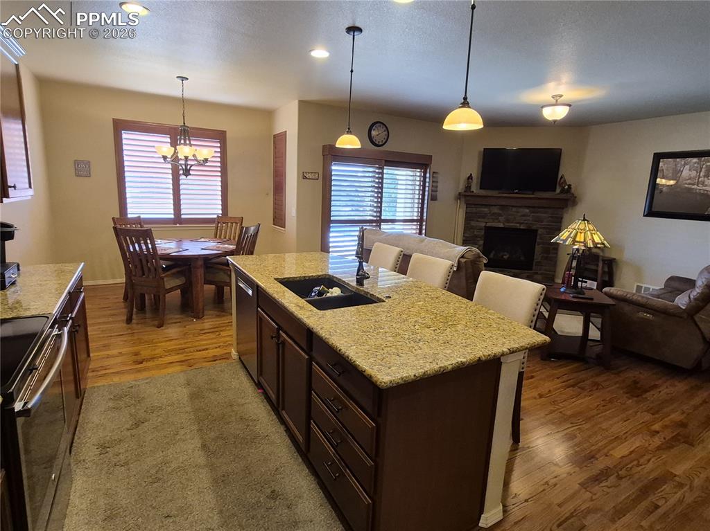 7619 Eagle Feather Point Colorado Springs, CO 80923 - Photo 8 of 23 a large kitchen with kitchen island a stove a sink a dining table and chairs