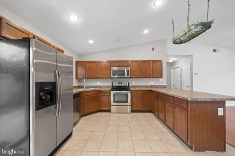 a large kitchen with stainless steel appliances kitchen island granite countertop a refrigerator and a sink