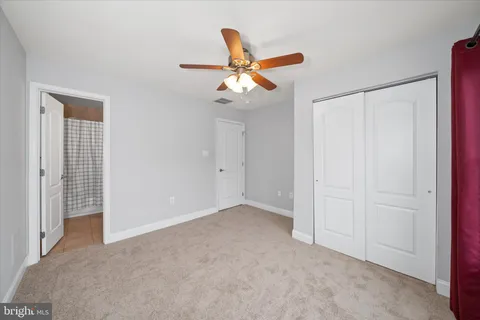 an empty room with closet and a ceiling fan