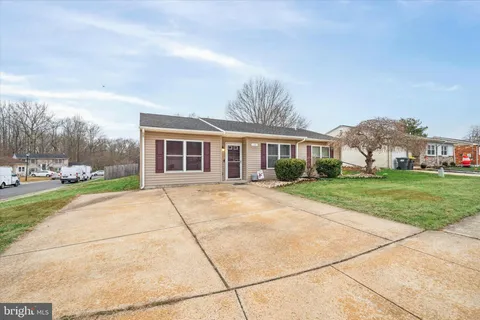 a view of house with yard street and trees in the background