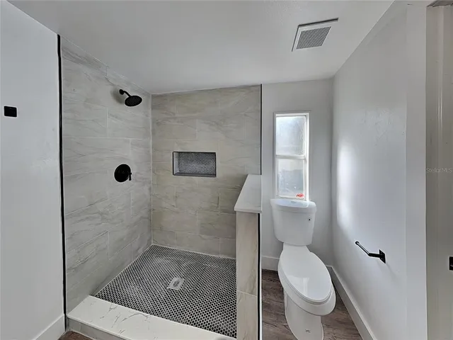 a bathroom with a granite countertop shower a toilet and a sink