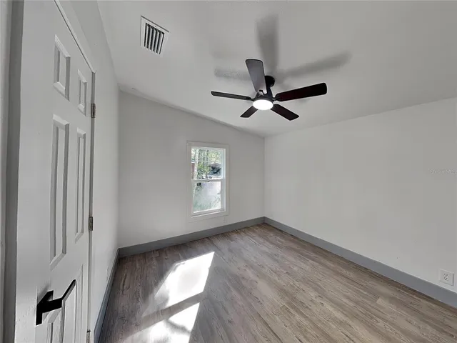 a view of room with a ceiling fan and wooden floor