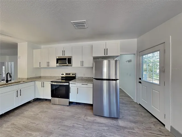 a kitchen with stainless steel appliances granite countertop a refrigerator sink and stove