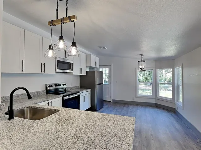 a kitchen with stainless steel appliances granite countertop a stove a sink dishwasher a refrigerator and microwave with wooden floor