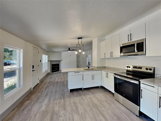a kitchen with granite countertop white cabinets a sink a window and stainless steel appliances