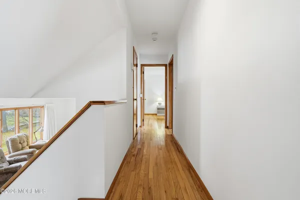 a view of a hallway with wooden floor and staircase