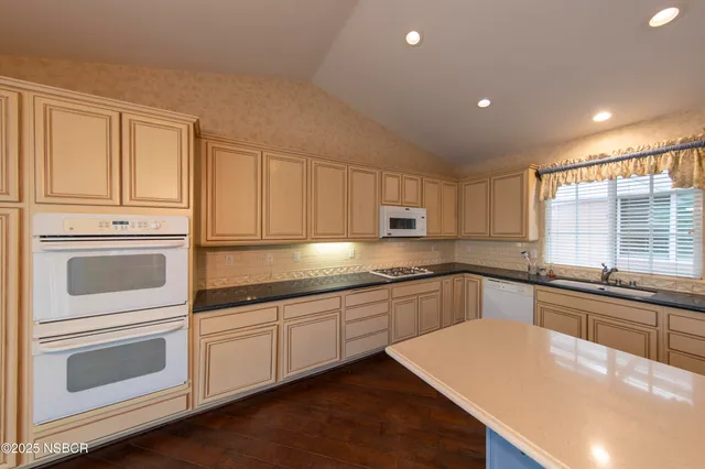 a large kitchen with granite countertop a large counter top and stainless steel appliances