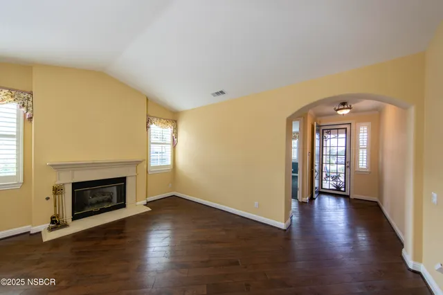 an empty room with wooden floor fireplace and windows