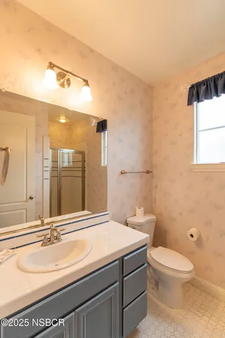 a bathroom with a granite countertop toilet sink and mirror