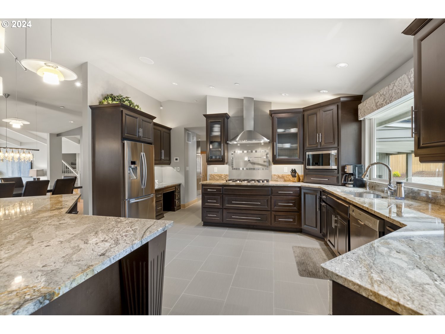 8857 Southwest Edgewood Street Tigard, OR 97223 - Photo 15 of 48 a kitchen with stainless steel appliances kitchen island granite countertop a refrigerator and cabinets