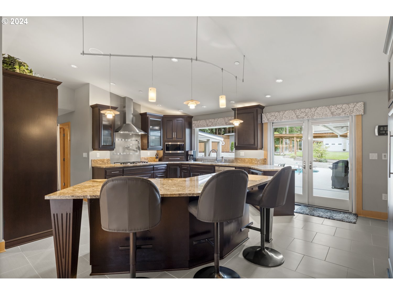 8857 Southwest Edgewood Street Tigard, OR 97223 - Photo 20 of 48 a dining hall with stainless steel appliances kitchen island granite countertop a table chairs and a refrigerator