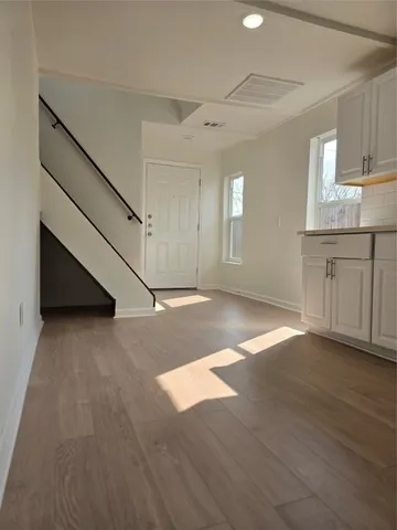 a view of an empty room with window and wooden floor