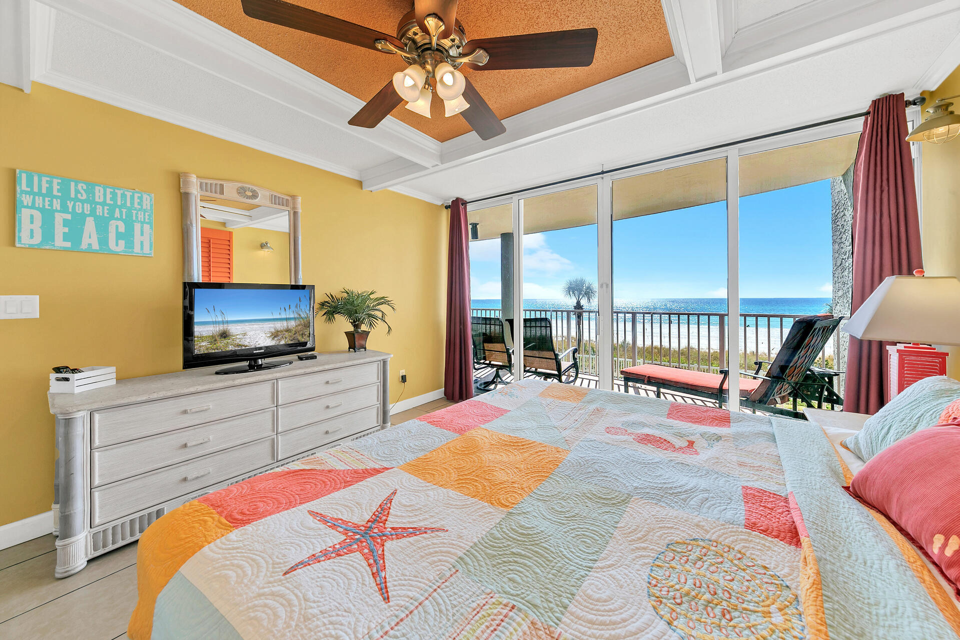 10515 Front Beach Road, Unit 102 Panama City Beach, FL 32407 - Photo 11 of 19 a bedroom with a bed a flat screen tv and a chandelier