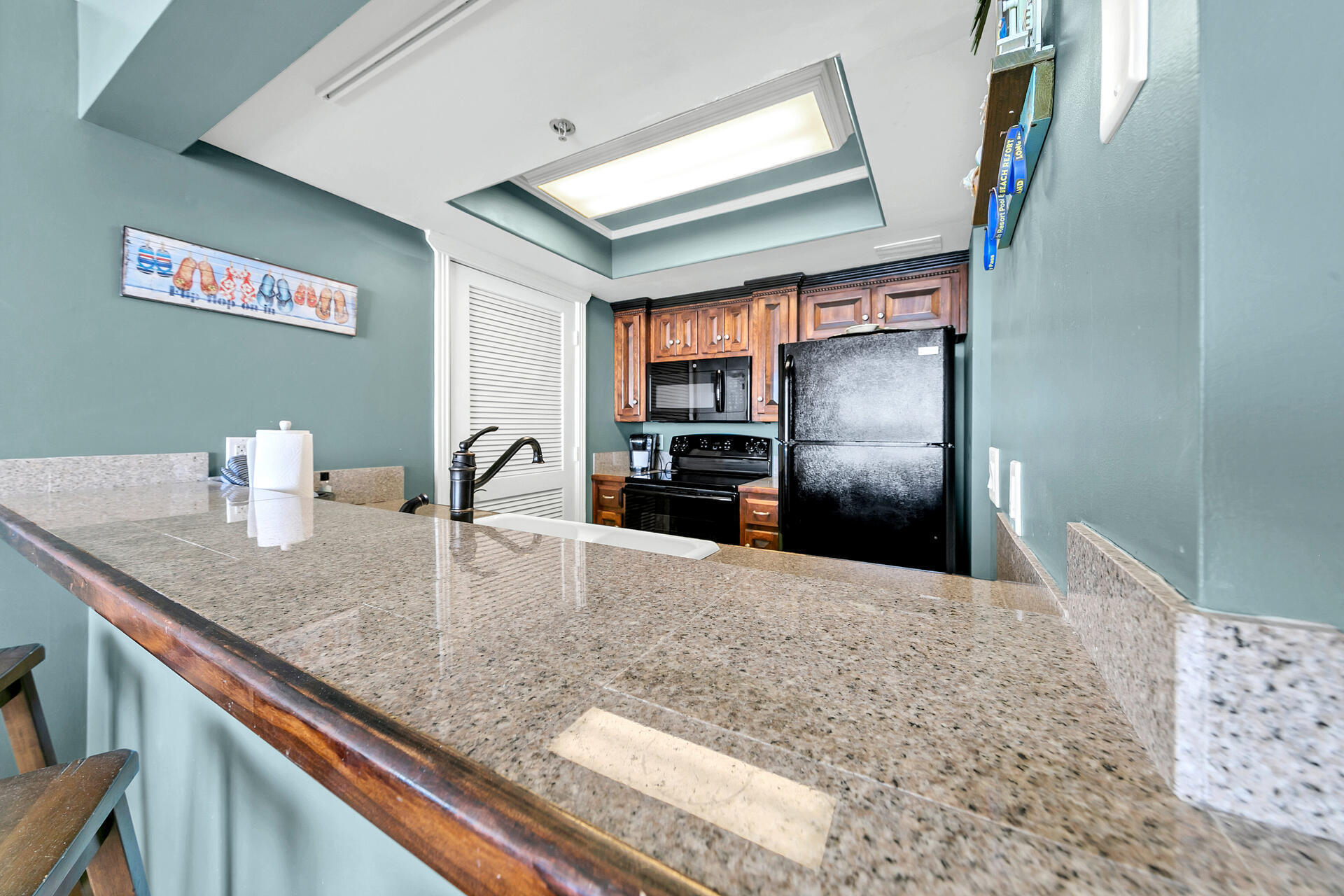 10515 Front Beach Road, Unit 102 Panama City Beach, FL 32407 - Photo 5 of 19 a kitchen with granite countertop a refrigerator and a sink