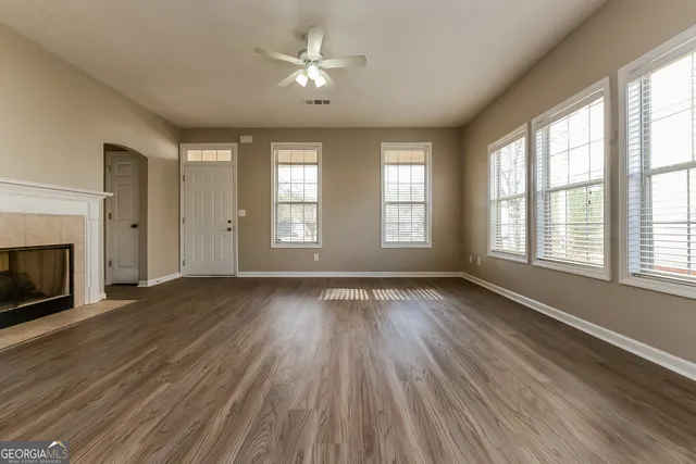 an empty room with wooden floor fireplace and windows