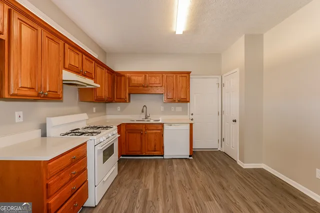 a kitchen with stainless steel appliances granite countertop a stove a sink dishwasher and a refrigerator with wooden floor