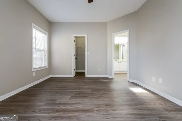 a view of an empty room with window and wooden floor
