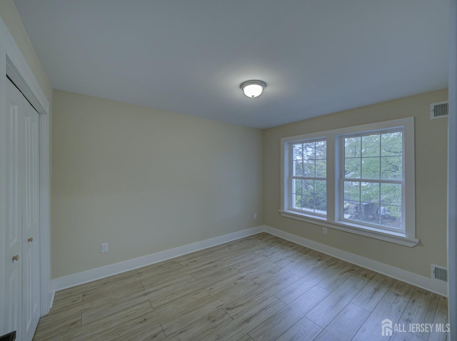 8 Travers Avenue, Unit 1 Edison, NJ 08817 - Photo 10 of 19 an empty room with wooden floor and windows
