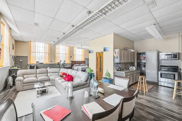 a living room with furniture kitchen view and a large window