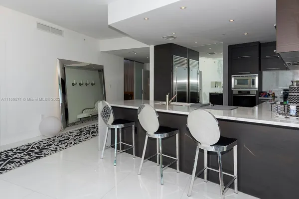 a kitchen with stainless steel appliances kitchen island granite countertop a refrigerator and a sink