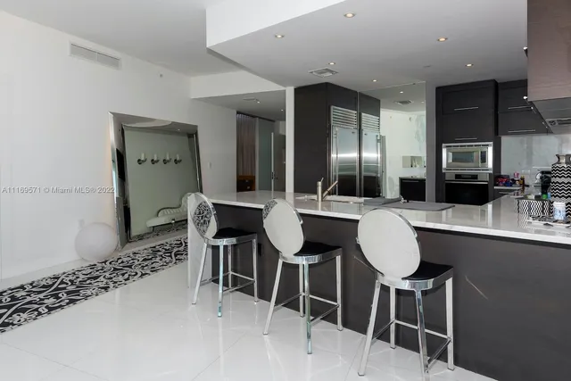 a kitchen with stainless steel appliances kitchen island granite countertop a refrigerator and a sink