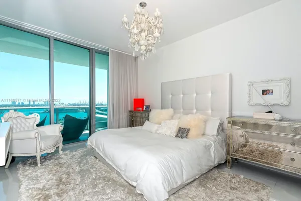 a bedroom with a bed a large window and a flat screen tv