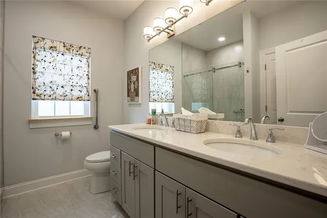 a bathroom with double vanity sinks a toilet a mirror and a window
