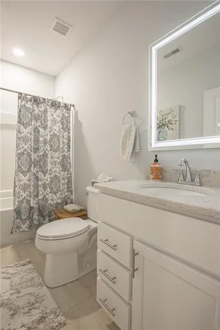 a bathroom with a granite countertop toilet sink and mirror