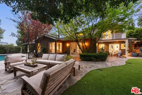 a view of a patio with couches table and chairs with plants and wooden fence